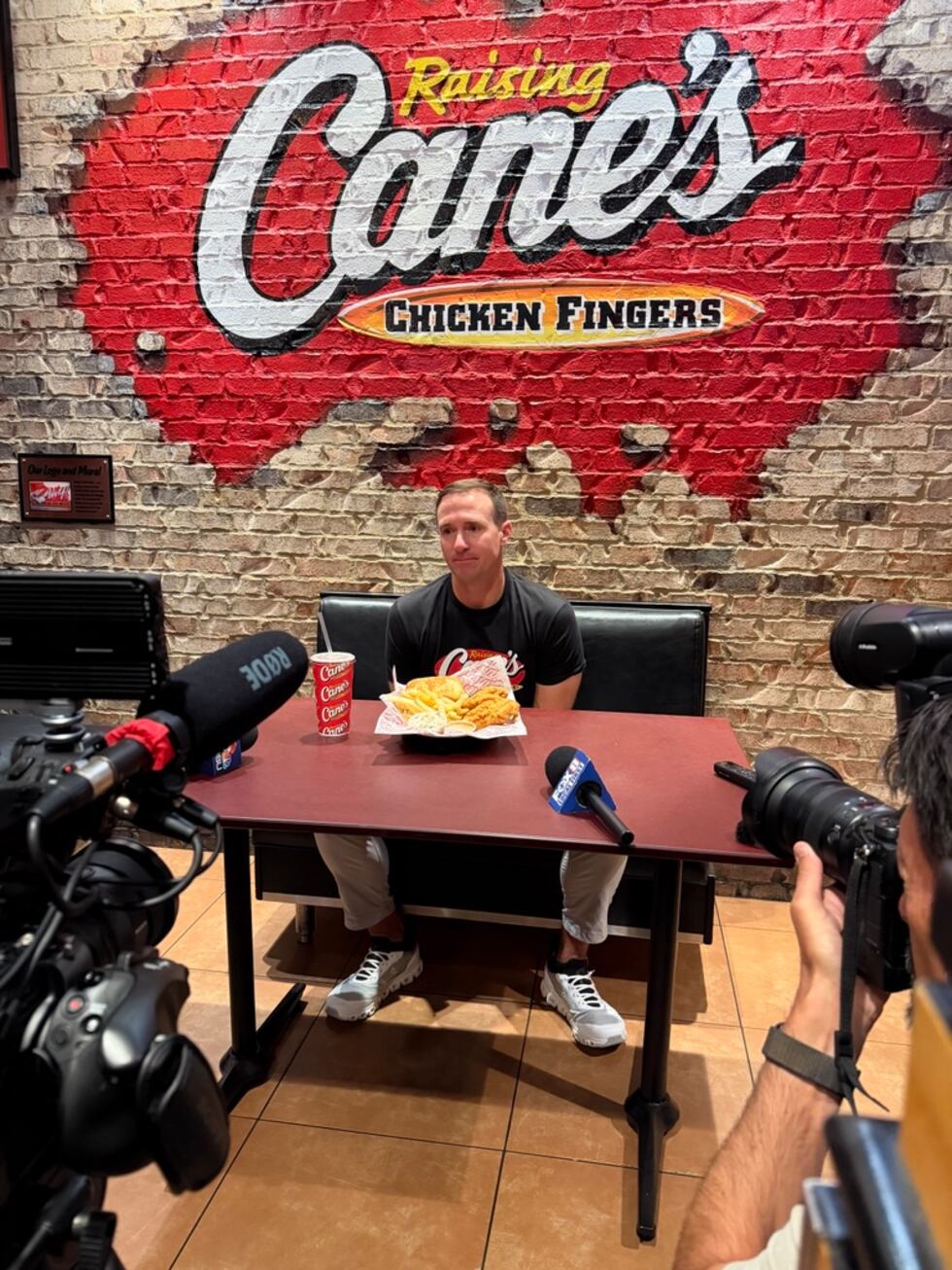 Drew Brees sits beneath a Raising Cane’s sign during his Hall of Fame weekend appearance.