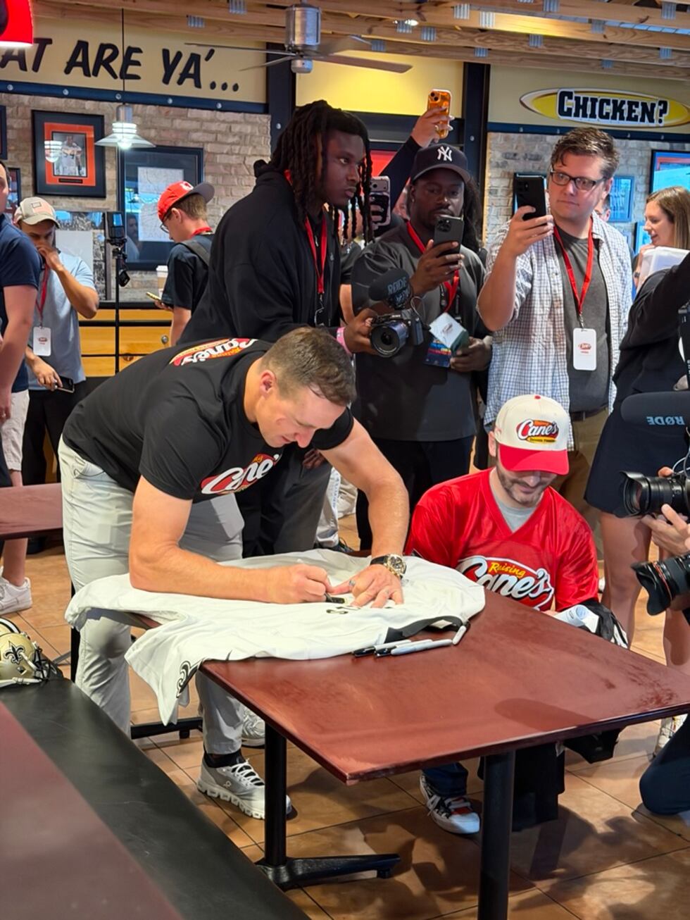 Drew Brees signs an item for a young fan during his Raising Cane’s appearance in Canton.