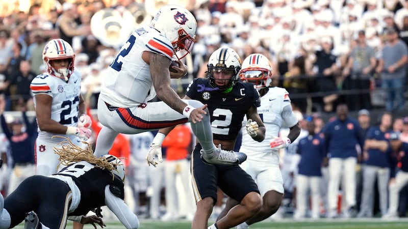 Auburn quarterback Ashton Daniels, center, leaps over Vanderbilt safety CJ Heard (8) to score...